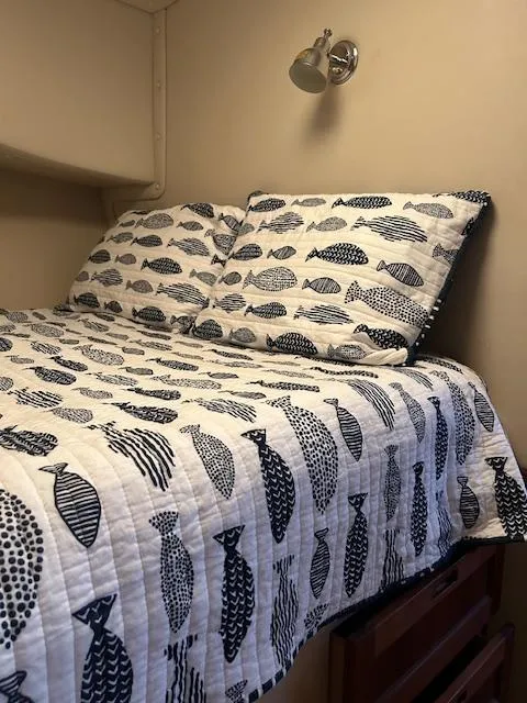 Slide: The Image of Cozy cabin bed in 2001 Nordic Tug 32, featuring fish-patterned bedding and wall-mounted reading light. - 13