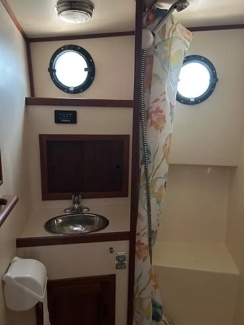 Slide: The Image of Nordic Tug 32 bathroom with sink, shower, and porthole windows, 2001 model. - 14