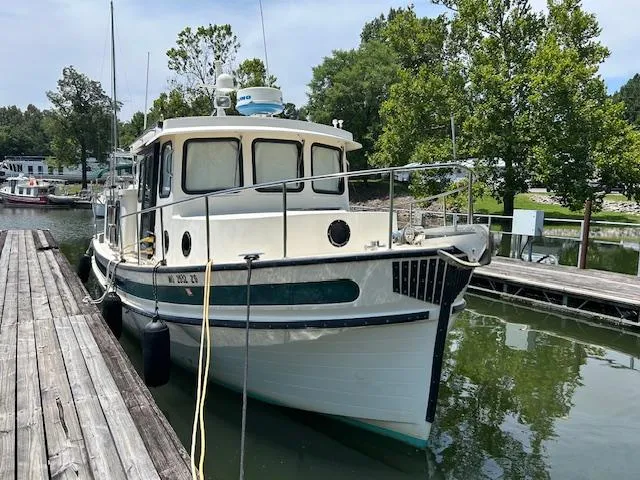 Slide: The Image of 2001 Nordic Tug 32 docked in a serene marina setting. - 2