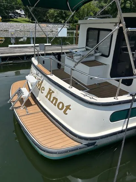 Slide: The Image of 2001 Nordic Tug 32 docked, featuring wooden deck and "Me Knot" name on stern. - 24