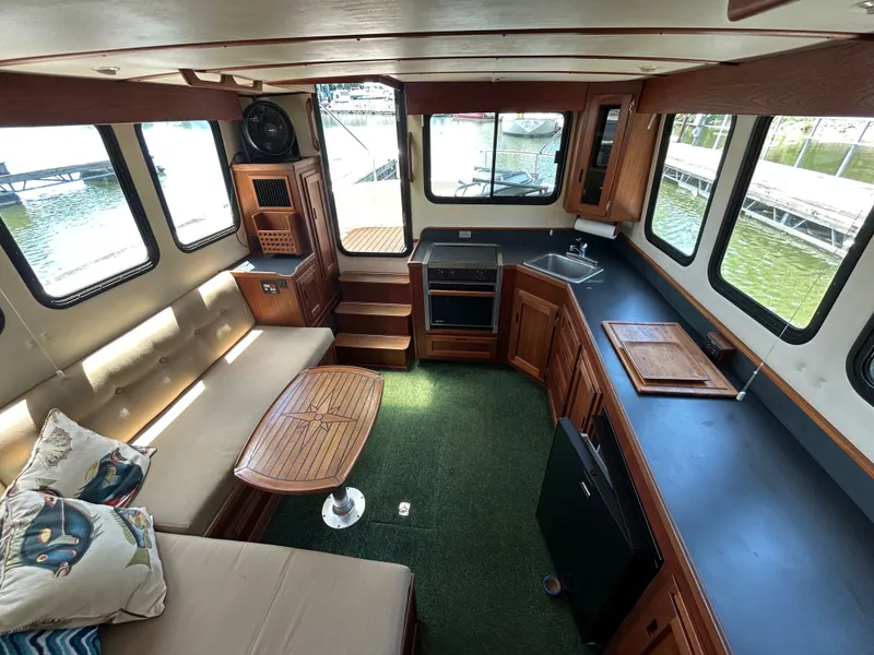 Slide: The Image of Interior of 2001 Nordic Tug 32 with cozy seating, kitchen, and large windows. - 29