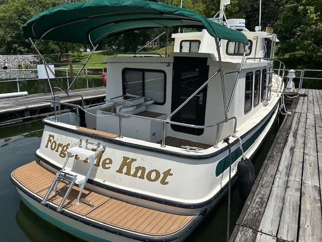 Slide: The Image of 2001 Nordic Tug 32 boat docked, featuring green canopy and "Forget Me Knot" name on stern. - 3