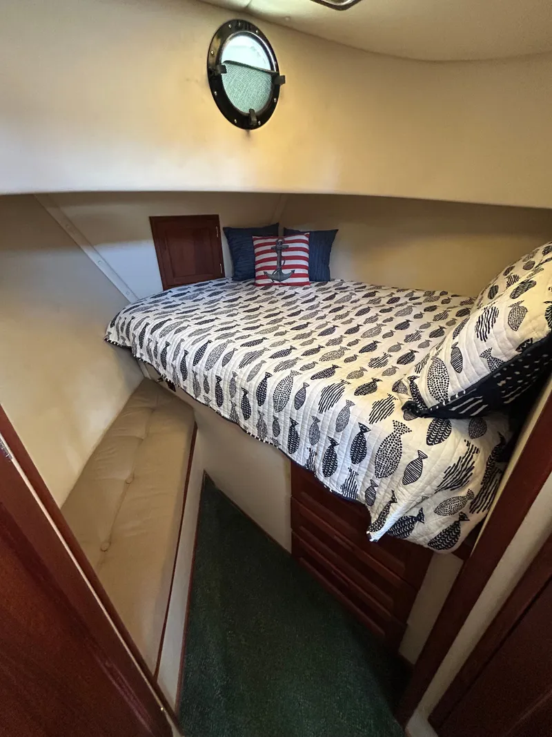 Slide: The Image of Cozy cabin interior of 2001 Nordic Tug 32 with patterned bedding and porthole window. - 33