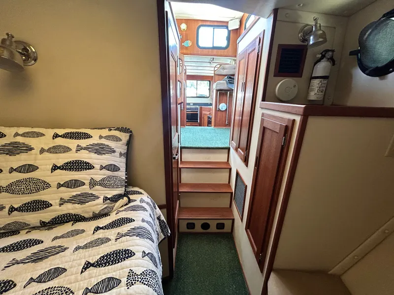 Slide: The Image of Cozy interior of 2001 Nordic Tug 32 with fish-patterned bedding and wooden cabinetry. - 34