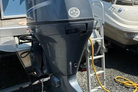 Slide: The Image of 2019 Bennington SSRX Pontoon 22 with outboard motor and ladder, parked on gravel. - 22