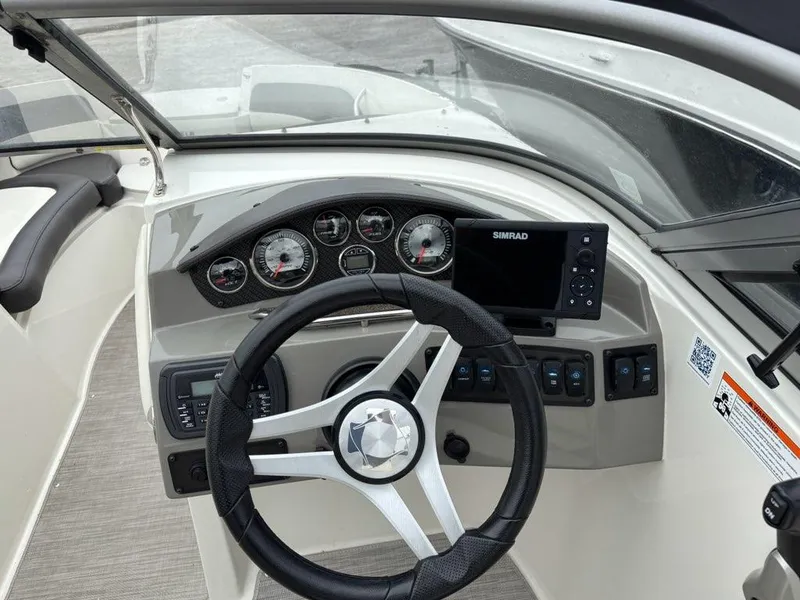 Slide: The Image of 2018 Stingray 214 LR boat dashboard with steering wheel, gauges, and Simrad display. - 12