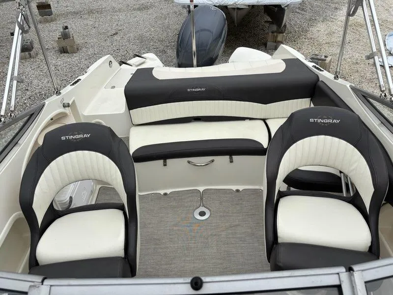 Slide: The Image of 2018 Stingray 214 LR boat interior with black and white seating, gray carpet. - 15