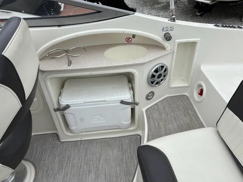 Slide: The Image of 2018 Stingray 214 LR boat interior with cooler, speaker, and seating area. - 16