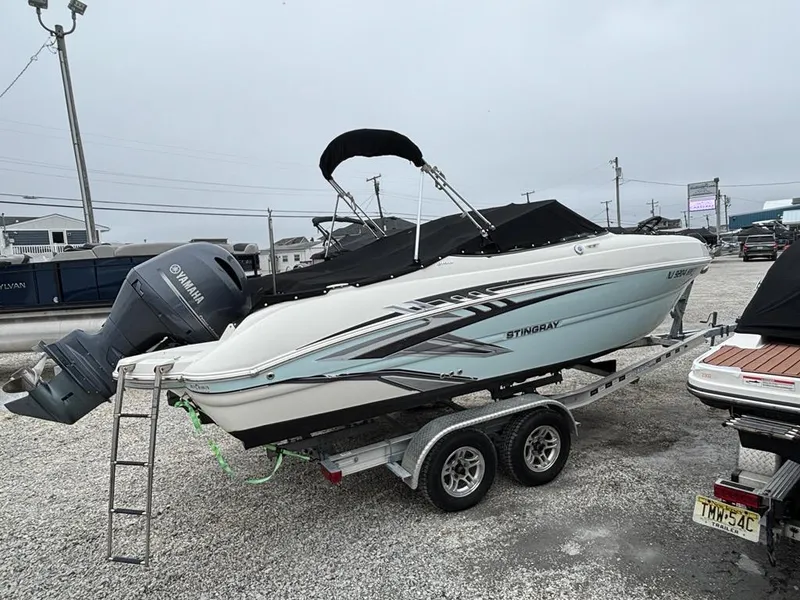 Slide: The Image of 2018 Stingray 214 LR boat on trailer with Yamaha outboard motor, parked in a gravel lot. - 3