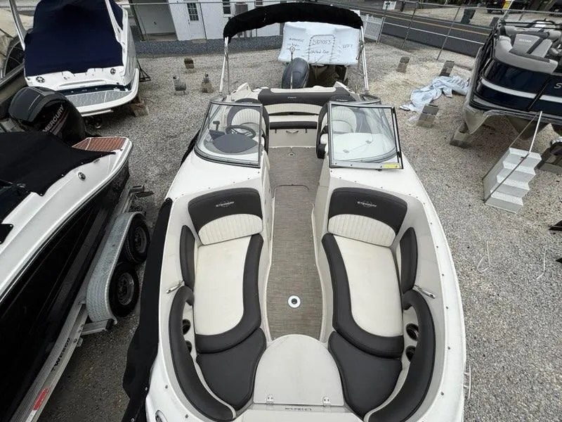 Slide: The Image of 2018 Stingray 214 LR boat with spacious seating, parked on gravel lot. - 6