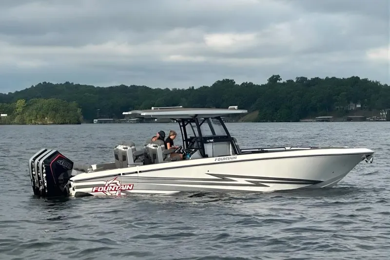 The Image of 2025 Fountain 34 SC boat cruising on a lake with scenic forest backdrop. - 0