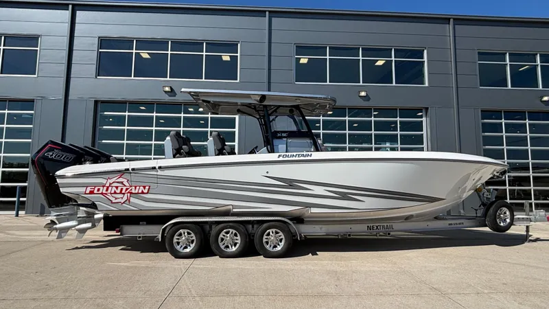 The Image of 2025 Fountain 34 SC boat on trailer, parked outside a modern building. - 1