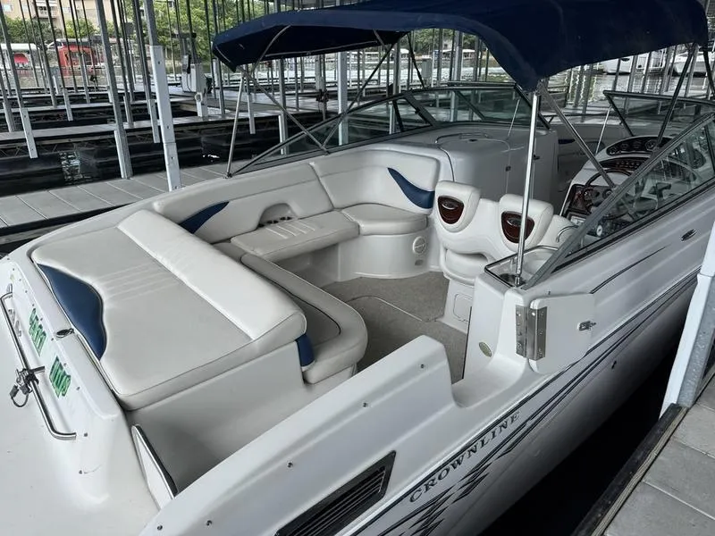 Slide: The Image of 2006 Crownline 290 BR boat with white seating and blue canopy in a marina. - 2