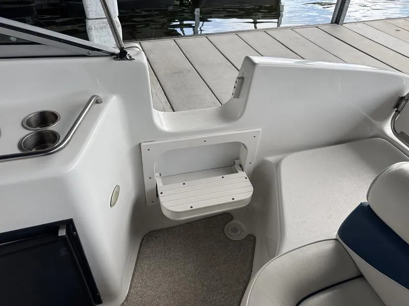 Slide: The Image of 2006 Crownline 290 BR boat interior with seating and cup holders near dock. - 4