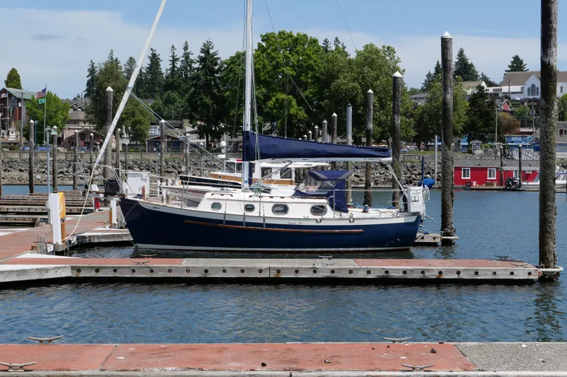 The Image of 1986 Pacific Seacraft Dana 24 sailboat docked in a marina with scenic background. - 0