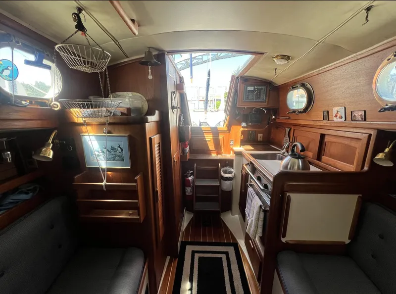Slide: The Image of Interior of 1986 Pacific Seacraft Dana 24 sailboat, featuring cozy wooden furnishings and compact kitchen. - 13