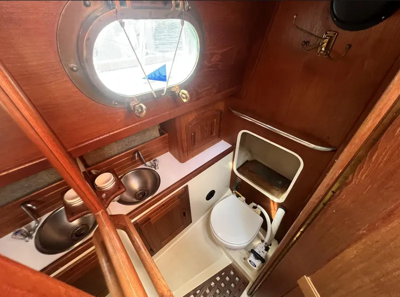Slide: The Image of 1986 Pacific Seacraft Dana 24 yacht bathroom with wooden interior and porthole window. - 14