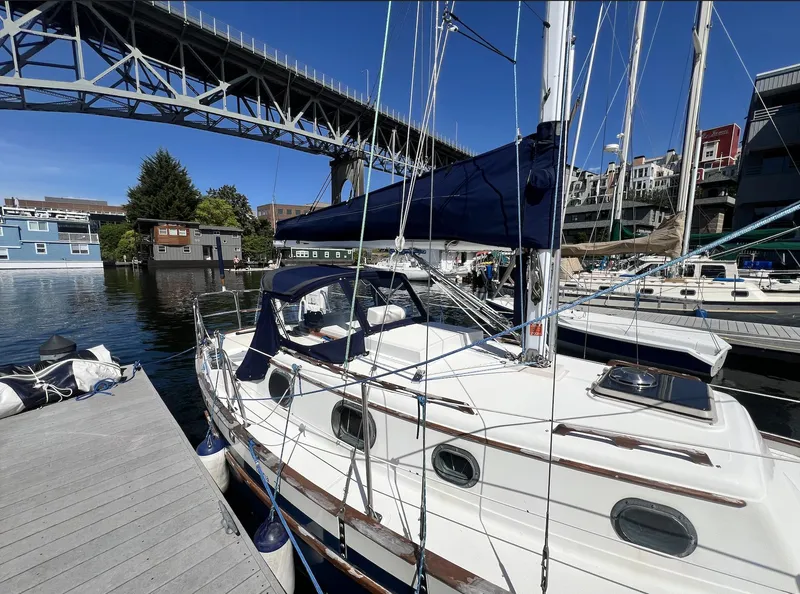 Slide: The Image of 1986 Pacific Seacraft Dana 24 sailboat docked near a bridge, surrounded by water and buildings. - 3