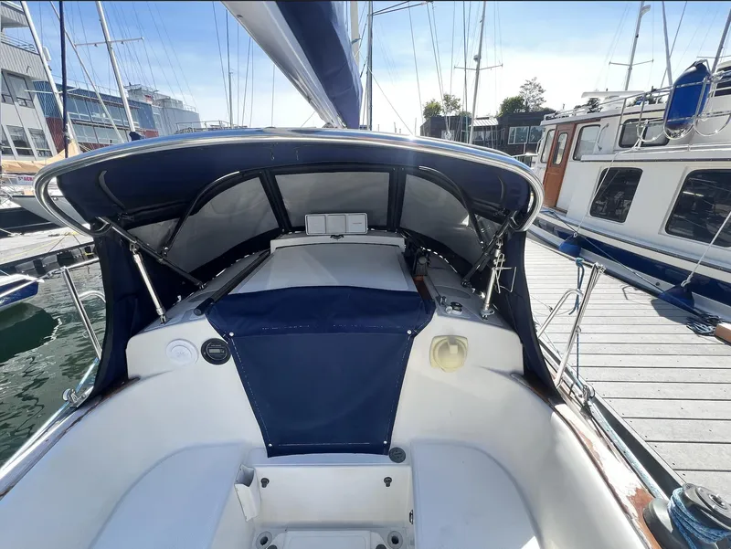Slide: The Image of 1986 Pacific Seacraft Dana 24 sailboat cockpit with blue canopy, docked at marina. - 5