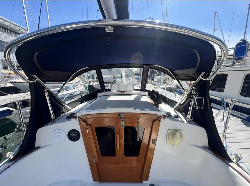 Slide: The Image of 1986 Pacific Seacraft Dana 24 sailboat cockpit with blue canopy, docked at marina. - 7