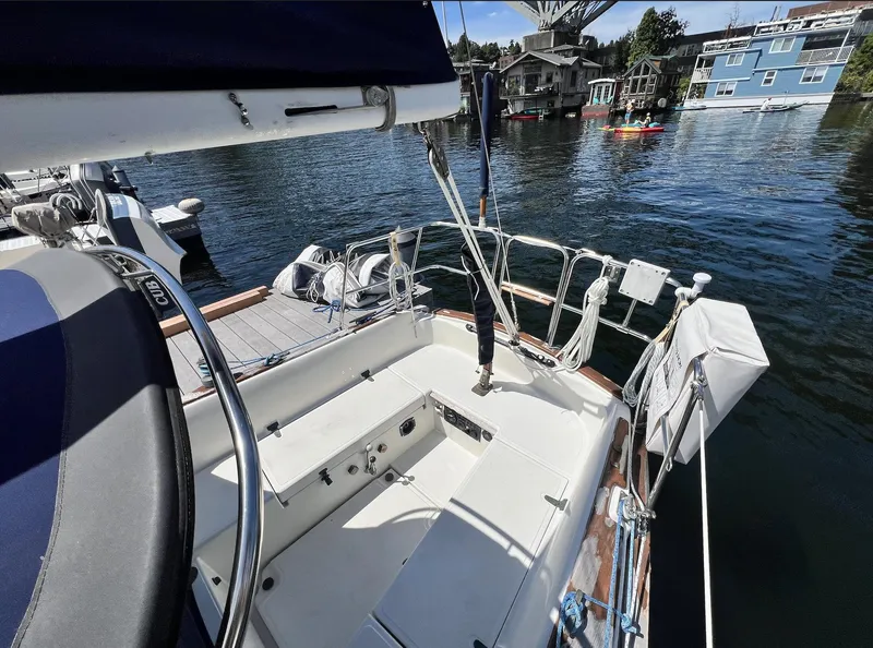 Slide: The Image of 1986 Pacific Seacraft Dana 24 sailboat docked, with scenic waterfront view and nearby kayakers. - 8