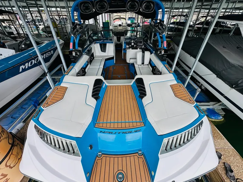 Slide: The Image of 2015 Nautique Super Air Nautique G23 boat with blue and white interior, docked in a marina. - 12