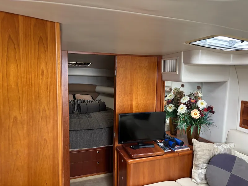 Slide: The Image of Interior of 2004 Riviera 4000 yacht with cozy bedroom, TV, and floral arrangement. - 11