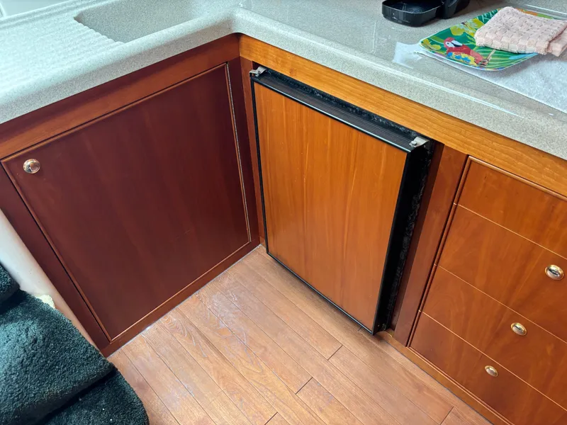 Slide: The Image of 2004 Riviera 4000 yacht interior with wooden cabinetry and compact fridge. - 14