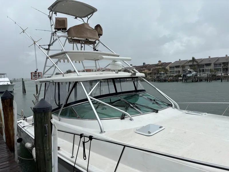 Slide: The Image of 2004 Riviera 4000 boat docked on a rainy day, with waterfront homes in the background. - 2