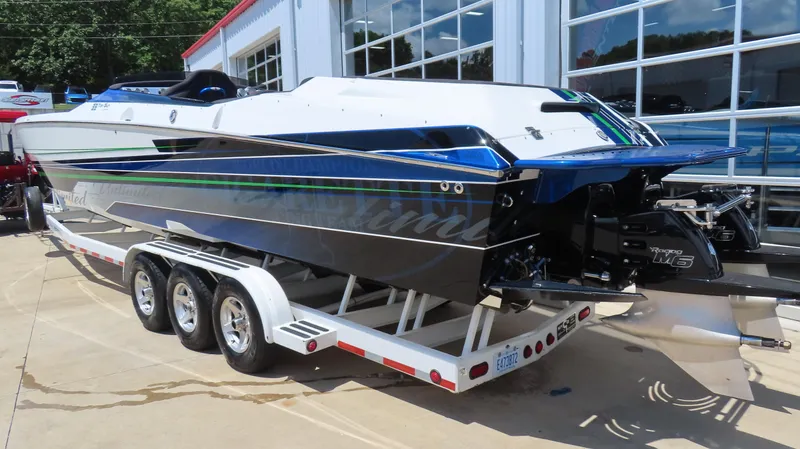 Slide: The Image of 2005 Cigarette 39' Top Gun Unlimited boat on trailer, parked outside a garage. - 7
