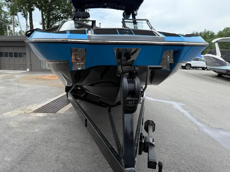 Slide: The Image of 2023 Centurion Fi23 boat on trailer, blue and black design, parked outdoors. - 11