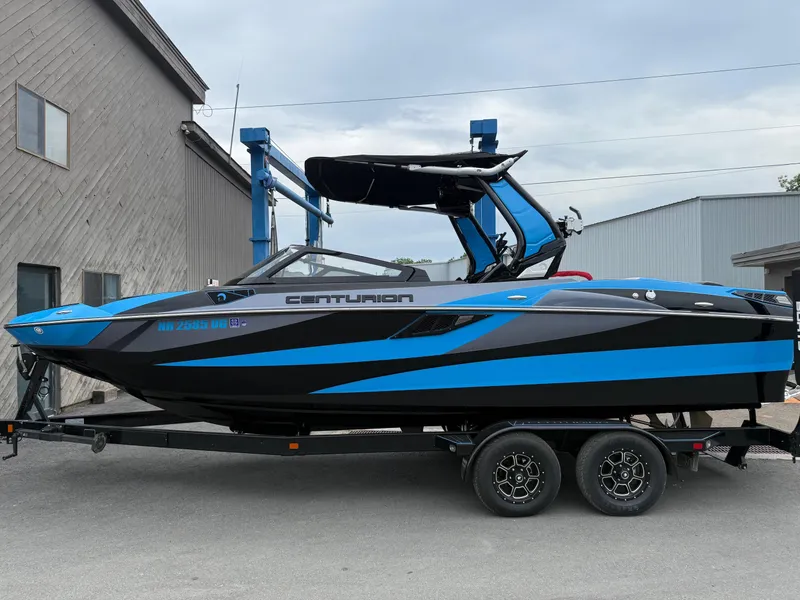 Slide: The Image of 2023 Centurion Fi23 boat with blue and black design on a trailer. - 2