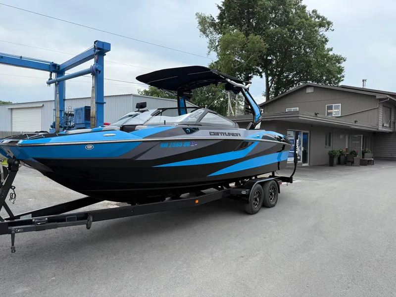 Slide: The Image of 2023 Centurion Fi23 boat on trailer, parked near a building, featuring blue and black design. - 3