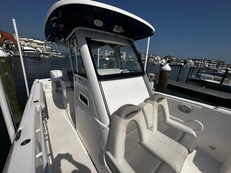 Slide: The Image of 2012 Everglades 295 Center Console boat docked at a marina, featuring sleek design and seating. - 13