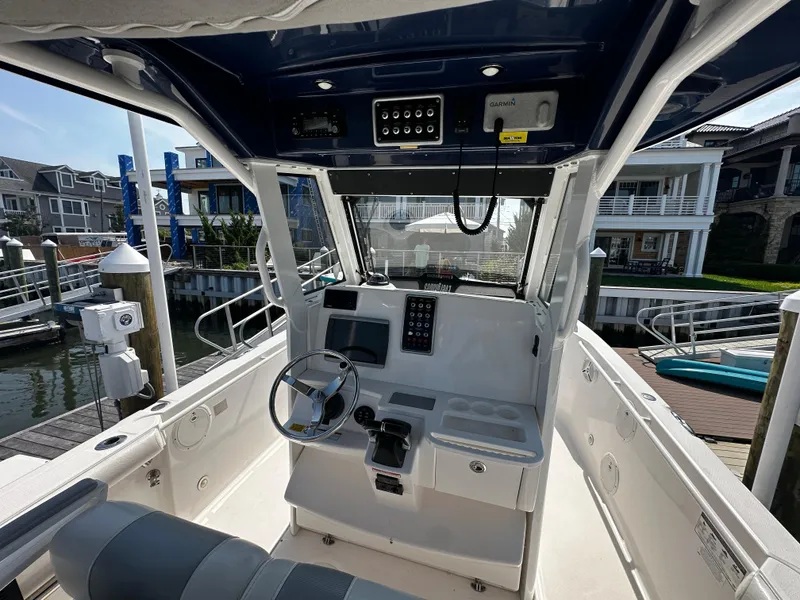 Slide: The Image of 2012 Everglades 295 Center Console boat interior at dock, featuring steering and control panel. - 14