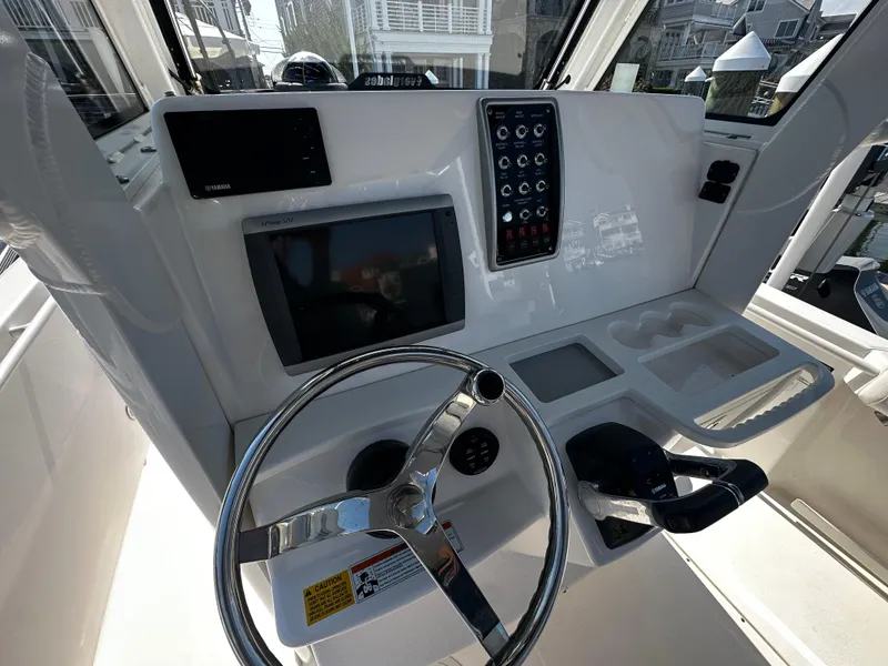 Slide: The Image of 2012 Everglades 295 Center Console helm with steering wheel, controls, and navigation display. - 15