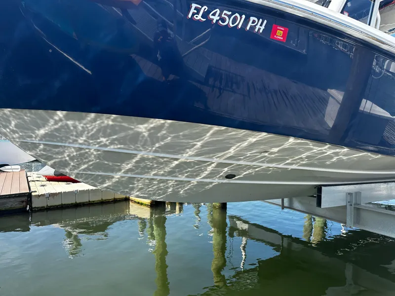 Slide: The Image of 2012 Everglades 295 Center Console boat docked, reflecting water patterns on hull. - 5