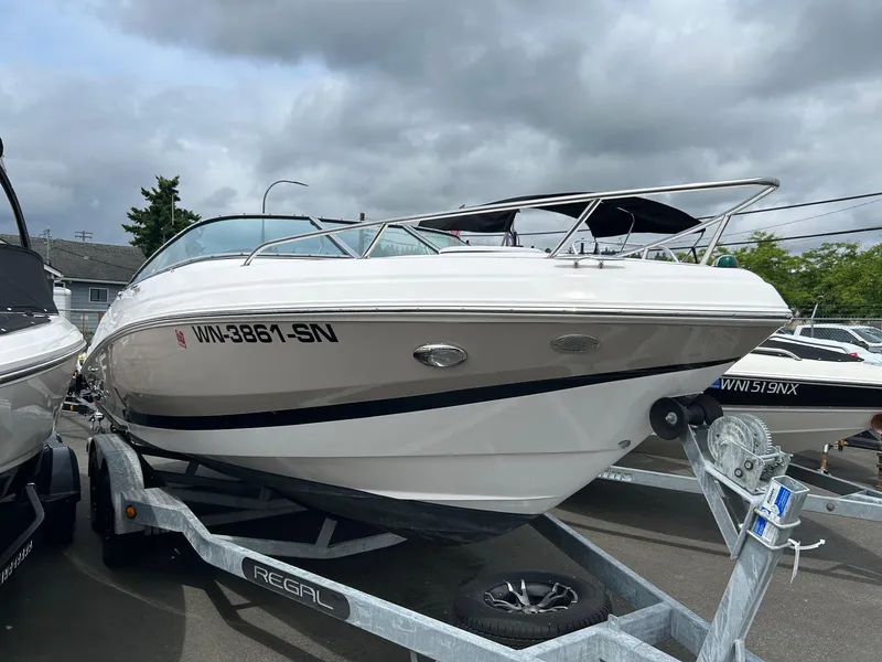 The Image of 2016 Regal 2250 Cuddy boat on trailer, parked outdoors under cloudy sky. - 1