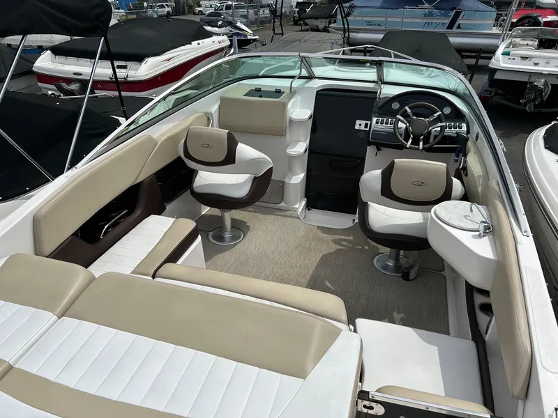 Slide: The Image of 2016 Regal 2250 Cuddy boat interior with beige and white seating, steering wheel, and dashboard. - 25