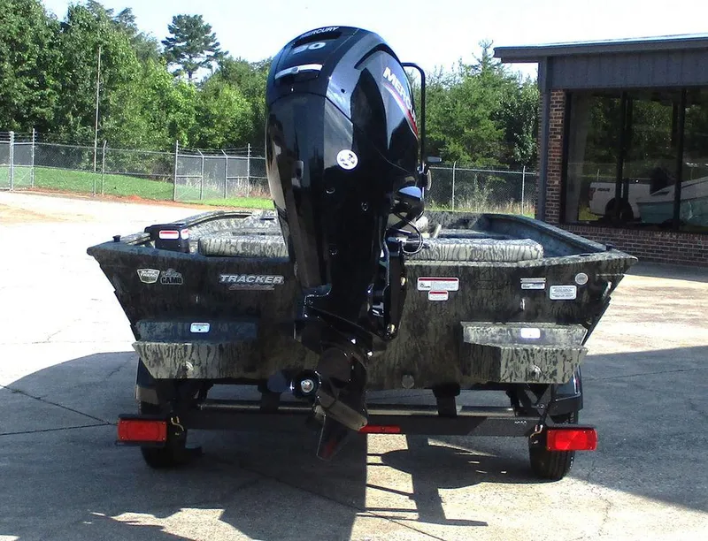 Slide: The Image of 2026 Tracker GRIZZLY® 1860 CC boat with Mercury outboard motor, parked outdoors. - 9