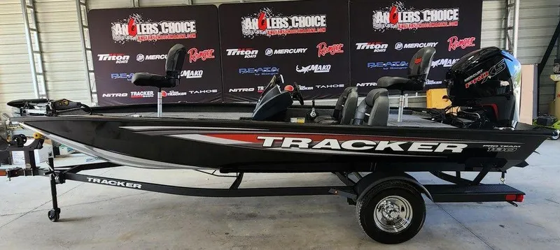 The Image of 2026 Tracker Pro Team 190 boat on trailer in showroom with branded backdrop. - 1
