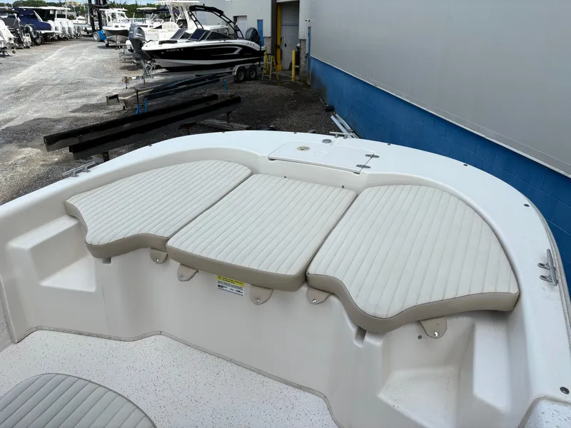 Slide: The Image of 2019 Carolina Skiff 198 DLV boat with cushioned seating, docked near other boats. - 16