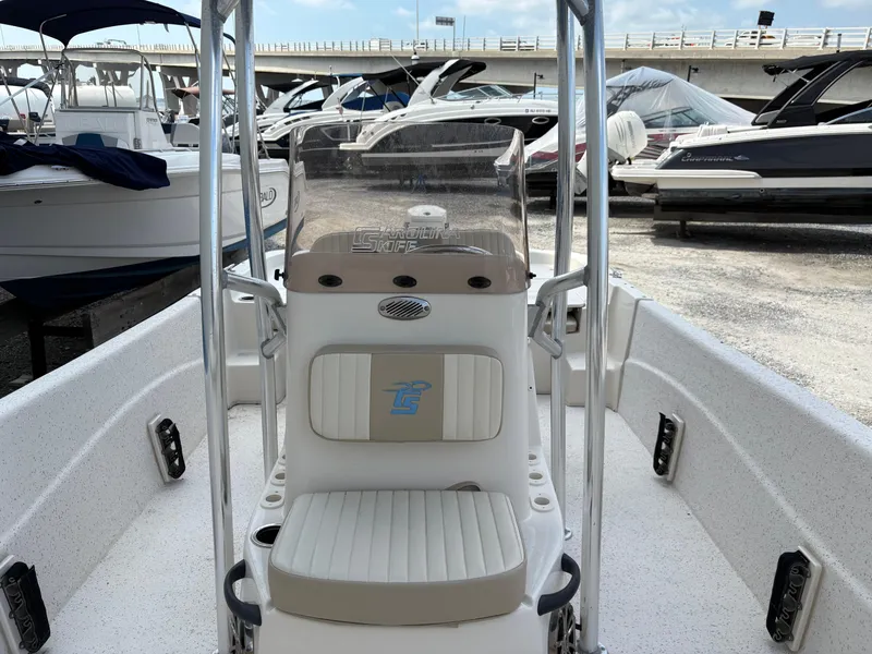 Slide: The Image of 2019 Carolina Skiff 198 DLV boat interior with seating and console, docked among other boats. - 18