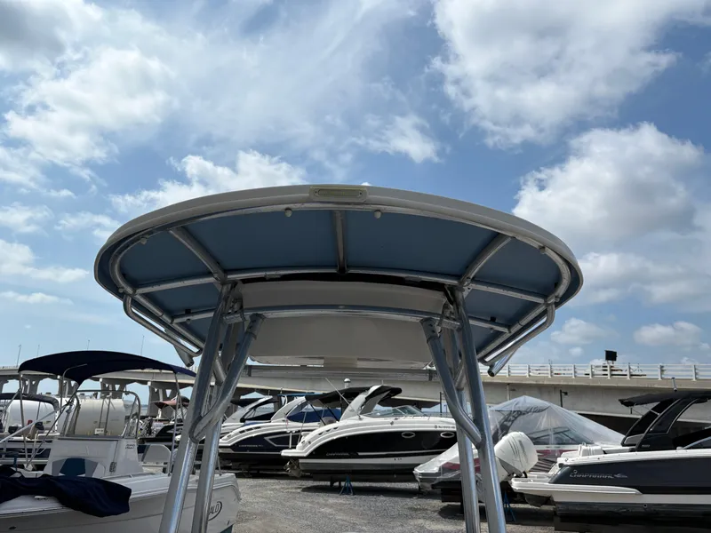 Slide: The Image of 2019 Carolina Skiff 198 DLV boat with T-top, docked under a partly cloudy sky. - 21