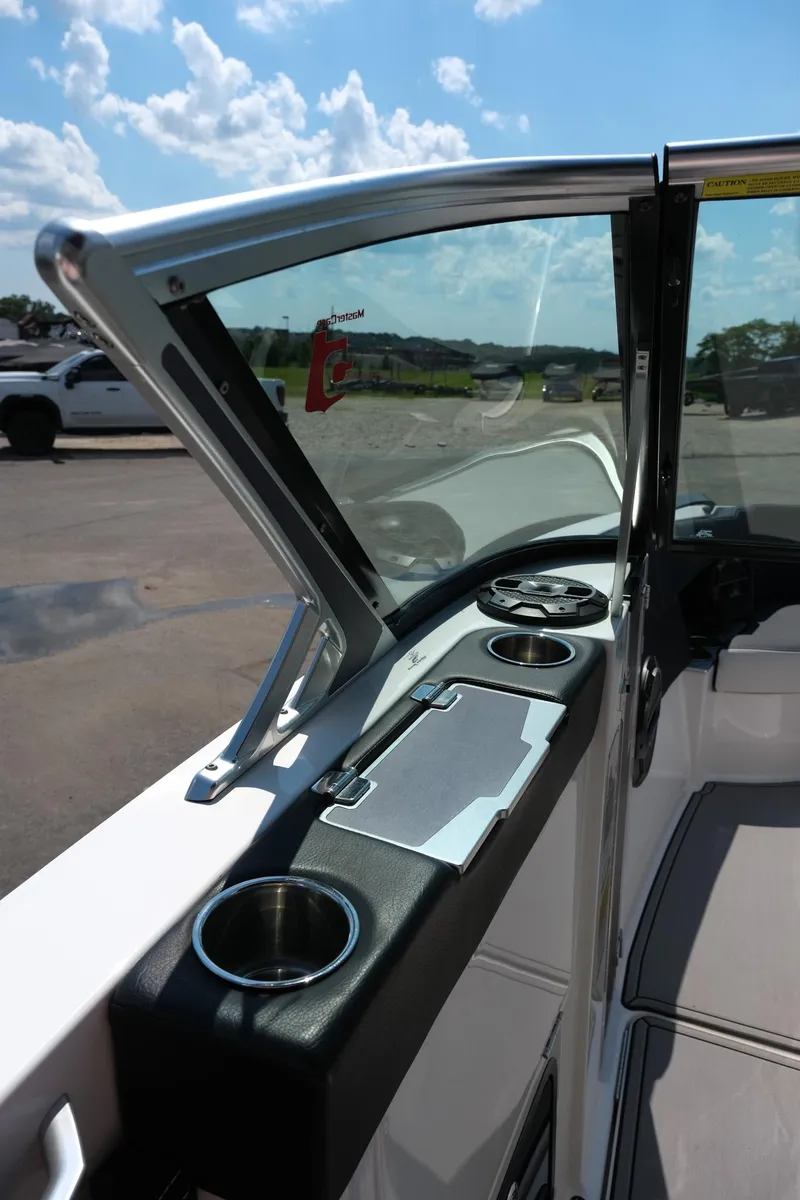Slide: The Image of 2021 MasterCraft X26 boat interior with cup holders and open windshield under blue sky. - 24