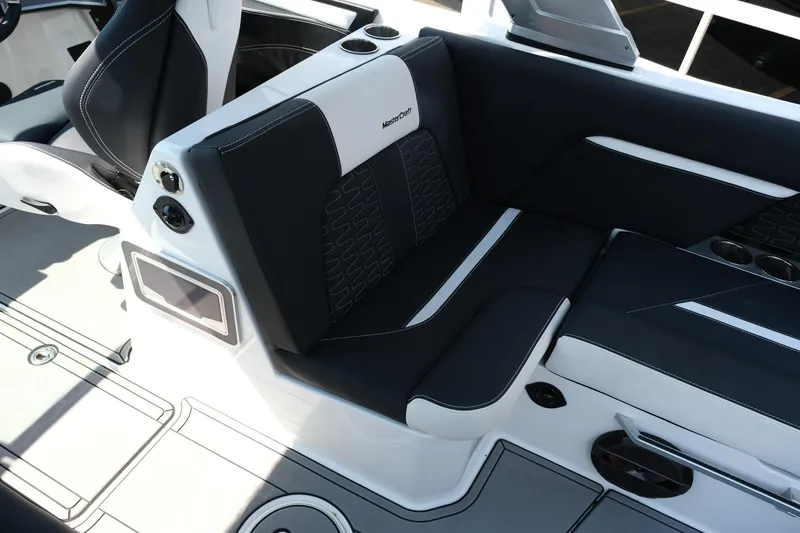 Slide: The Image of 2021 MasterCraft X26 boat interior with black and white seating and cup holders. - 26
