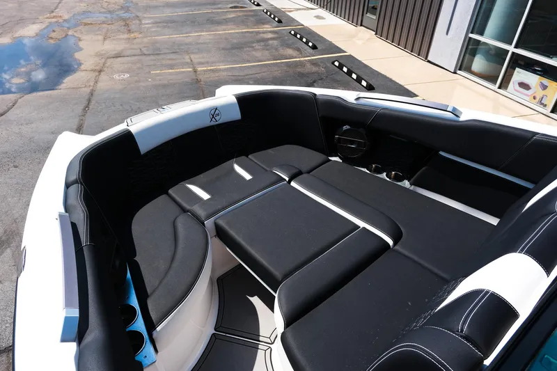 Slide: The Image of 2021 MasterCraft X26 boat interior with black and white seating in a parking lot. - 29
