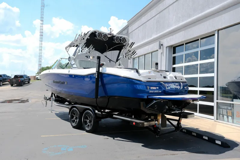 Slide: The Image of 2021 MasterCraft X26 boat on trailer, blue and white, parked outside a showroom. - 4
