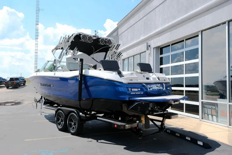 Slide: The Image of 2021 MasterCraft X26 boat on trailer, blue and white, parked outside a building. - 5