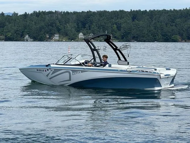 Slide: The Image of 2019 Tigé R21 boat cruising on a lake with forested shoreline in the background. - 10